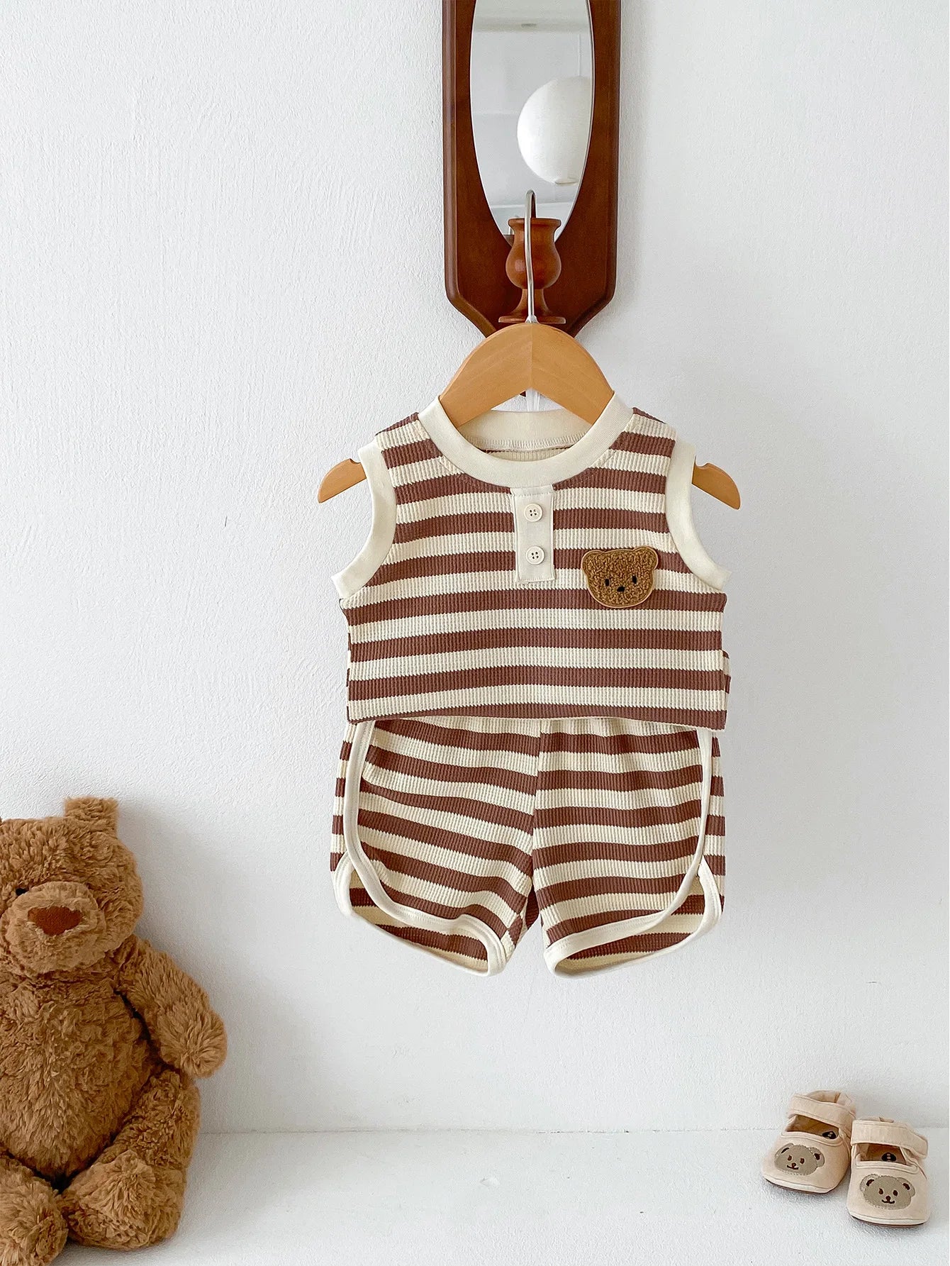 MILANCEL 2024 baby sleeveless set featuring brown and cream striped tee and shorts with bear patch, hanging with teddy bear.